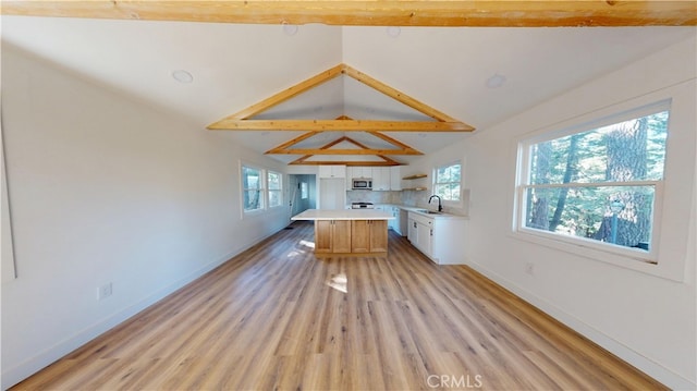 kitchen featuring plenty of natural light, stainless steel microwave, light countertops, and a sink