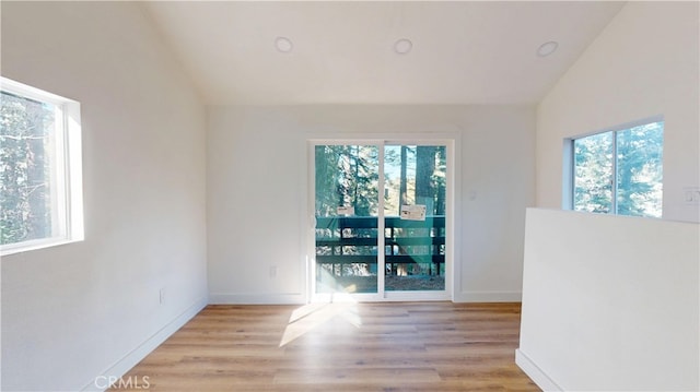 spare room featuring lofted ceiling, baseboards, and wood finished floors