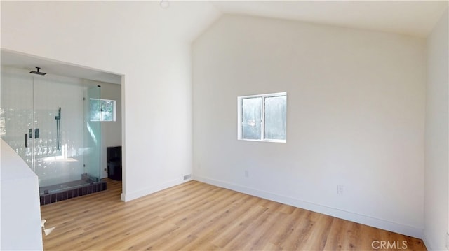 empty room featuring visible vents, vaulted ceiling, baseboards, and wood finished floors