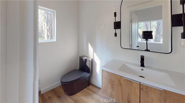 half bathroom featuring toilet, baseboards, wood finished floors, and vanity