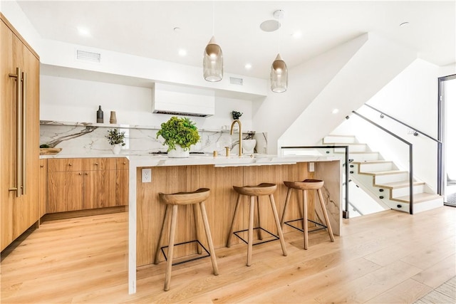 kitchen with light wood-style floors, a wall mounted air conditioner, decorative backsplash, and modern cabinets