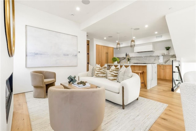 living area with light wood-style floors, visible vents, and recessed lighting