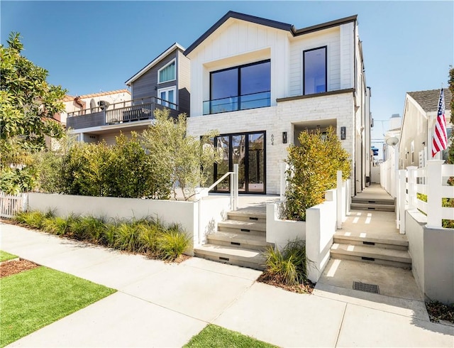 modern home with stone siding, fence, and board and batten siding