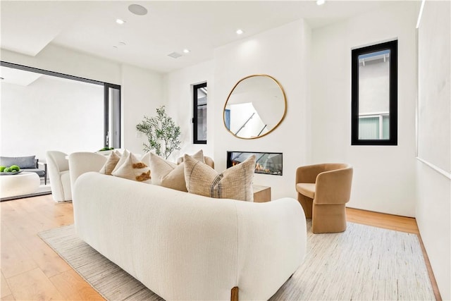 living room featuring light wood finished floors, recessed lighting, and a glass covered fireplace