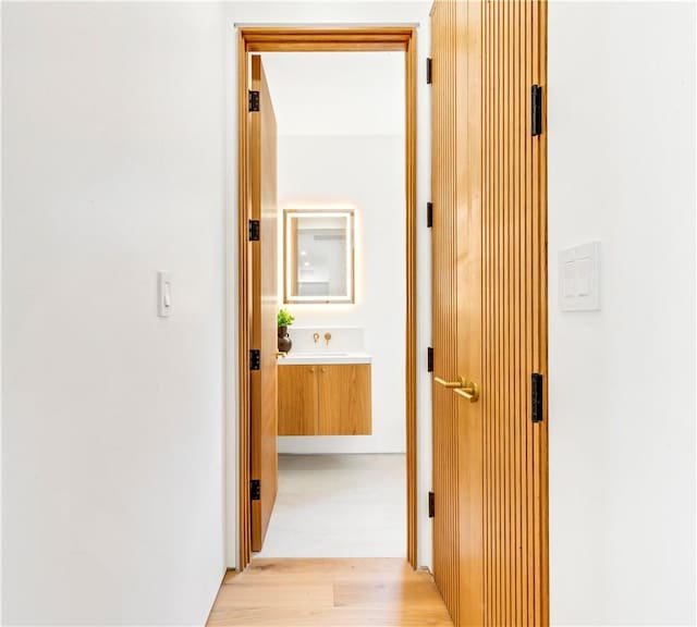 hallway featuring light wood-style flooring and a sink