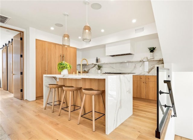 kitchen with visible vents, light wood finished floors, custom exhaust hood, and modern cabinets