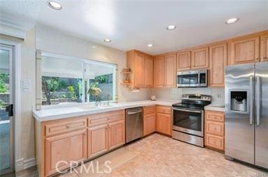 kitchen featuring stainless steel appliances, recessed lighting, light countertops, and light brown cabinetry