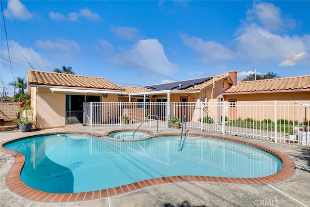 view of swimming pool featuring a patio, fence, and a pool with connected hot tub