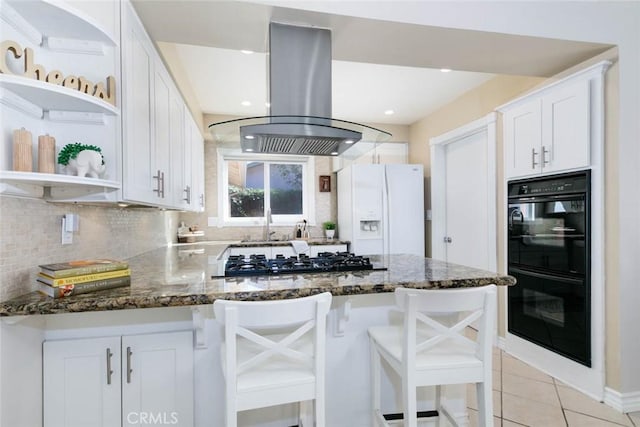 kitchen with white refrigerator with ice dispenser, island exhaust hood, gas stovetop, open shelves, and dobule oven black