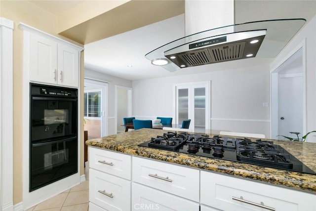 kitchen with black appliances, island range hood, white cabinetry, and dark stone counters