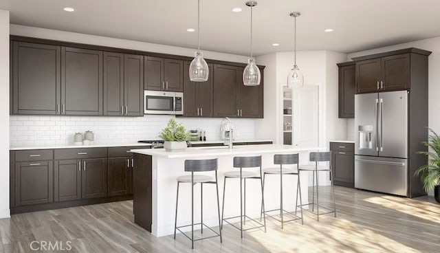 kitchen with light wood-style flooring, stainless steel appliances, a breakfast bar, dark brown cabinets, and decorative light fixtures