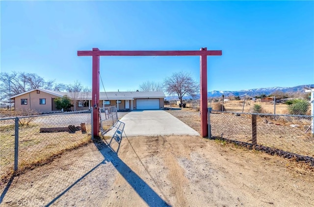 ranch-style home with concrete driveway, fence, an attached garage, and a mountain view