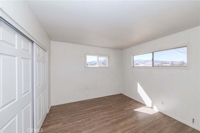 unfurnished bedroom with a closet, baseboards, and wood finished floors