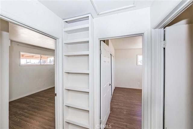 corridor featuring attic access, baseboards, and wood finished floors