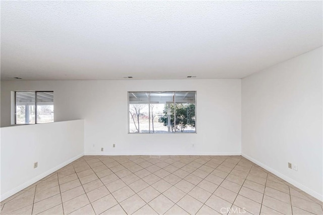 spare room featuring plenty of natural light, visible vents, and a textured ceiling