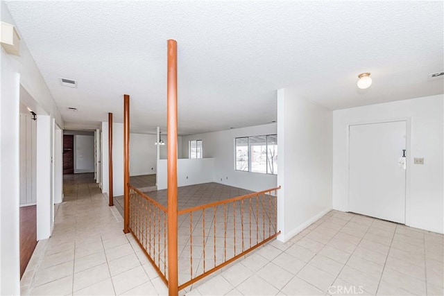 interior space featuring light tile patterned floors, visible vents, and a textured ceiling