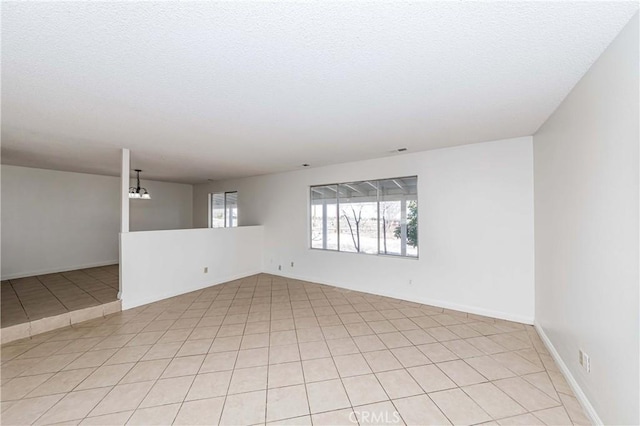 unfurnished room with a textured ceiling, light tile patterned floors, visible vents, and an inviting chandelier