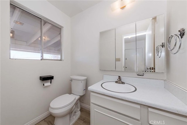 bathroom featuring toilet, baseboards, wood finished floors, and vanity