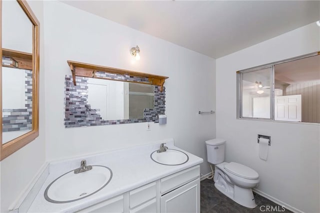 full bath featuring double vanity, a sink, toilet, and baseboards