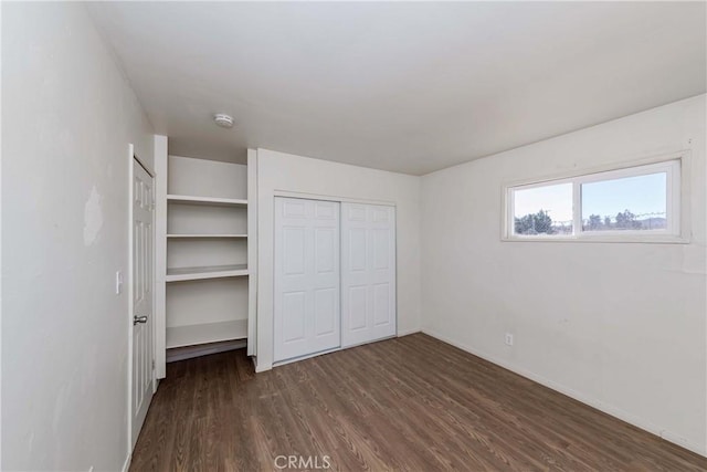 unfurnished bedroom featuring dark wood-style flooring and baseboards