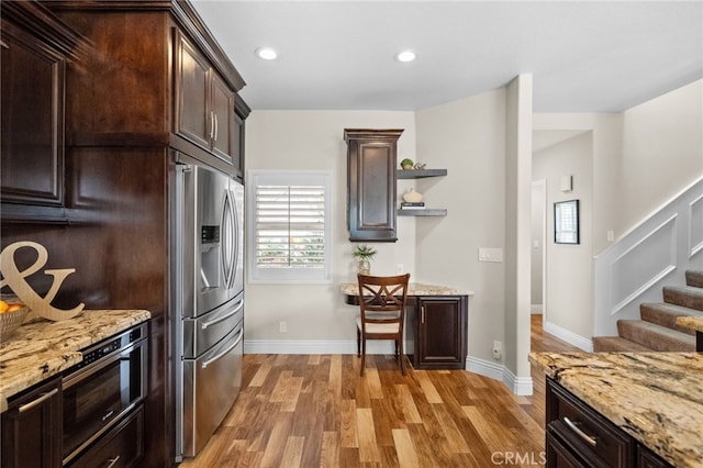 kitchen with dark brown cabinets, appliances with stainless steel finishes, open shelves, and light wood-style flooring