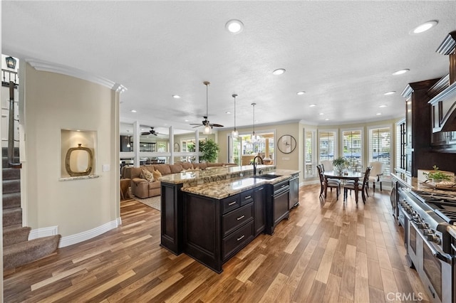 kitchen with a kitchen island with sink, open floor plan, double oven range, and wood finished floors