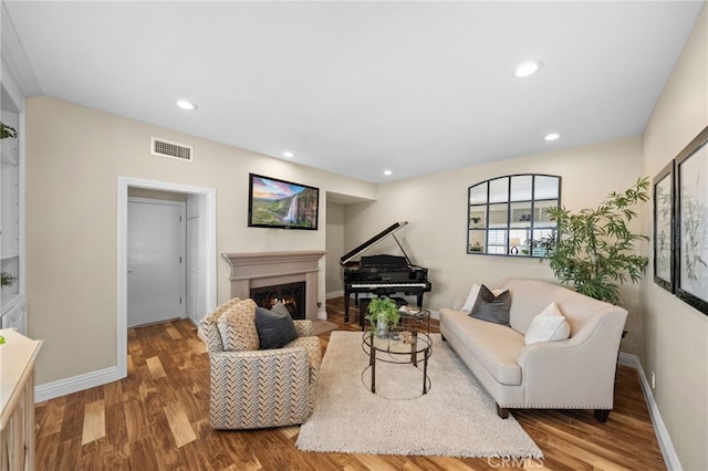 living room with a fireplace with flush hearth, recessed lighting, visible vents, and wood finished floors