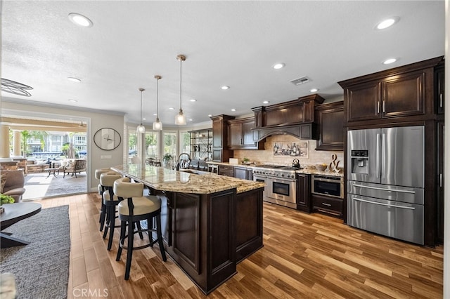 kitchen featuring dark brown cabinetry, custom range hood, visible vents, and stainless steel appliances