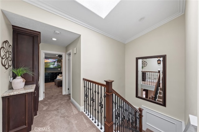 hallway with baseboards, light colored carpet, crown molding, and an upstairs landing