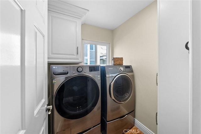 laundry room featuring baseboards, cabinet space, and washing machine and clothes dryer