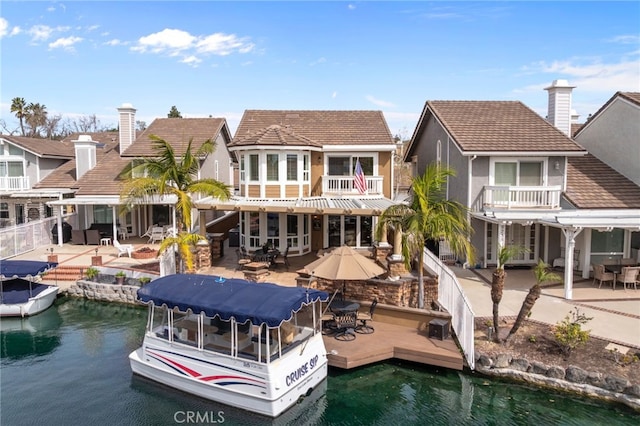 rear view of house featuring a patio area, a water view, and a balcony