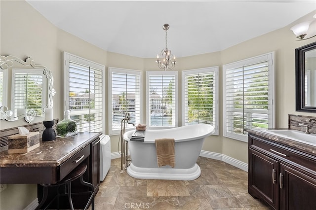 full bathroom with a chandelier, a freestanding tub, a healthy amount of sunlight, and baseboards