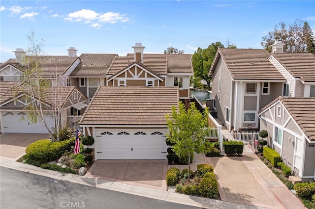 view of front of property featuring fence, concrete driveway, a tiled roof, stucco siding, and a chimney