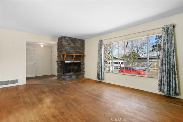 unfurnished living room featuring visible vents, a fireplace, and wood finished floors