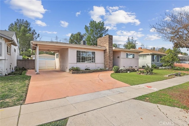 single story home featuring driveway, an attached carport, fence, a front lawn, and stucco siding