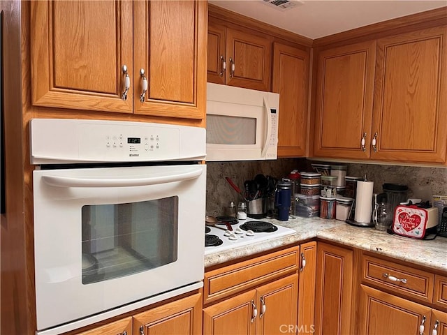 kitchen featuring white appliances, visible vents, brown cabinetry, light countertops, and backsplash