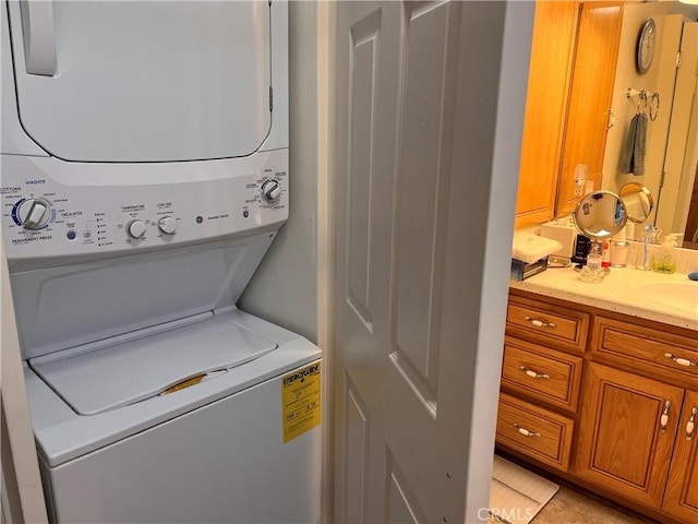 washroom with laundry area, stacked washer / dryer, and a sink