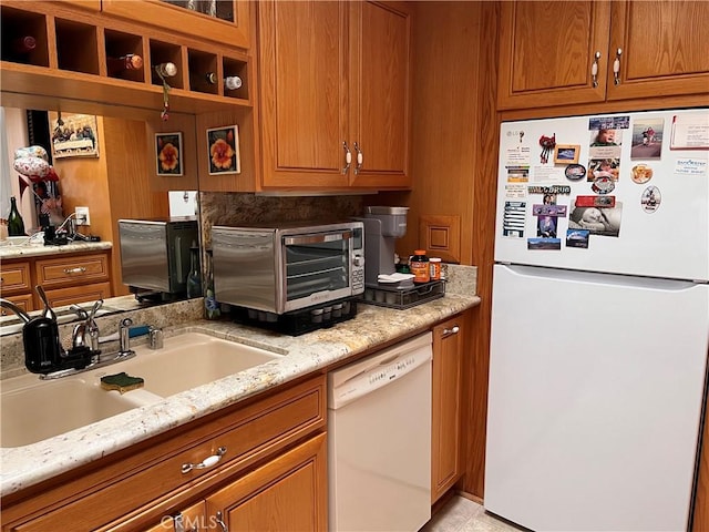 kitchen with white appliances, a toaster, brown cabinets, and a sink