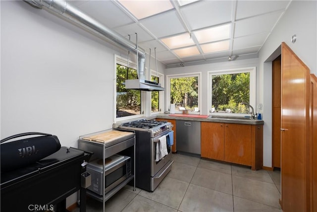 kitchen featuring light tile patterned floors, appliances with stainless steel finishes, brown cabinetry, and a sink