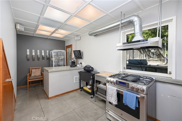 kitchen featuring range hood, light tile patterned floors, open shelves, gas range, and baseboards