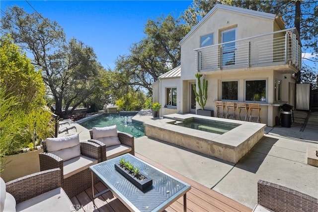 back of property featuring a balcony, an in ground hot tub, an outdoor living space, outdoor dry bar, and an outdoor pool