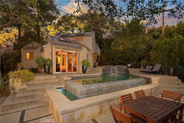 pool at dusk featuring an outdoor pool, an exterior structure, a patio area, an outdoor structure, and outdoor dining space