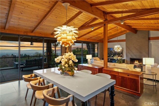 sunroom featuring plenty of natural light, a large fireplace, vaulted ceiling with beams, and an inviting chandelier