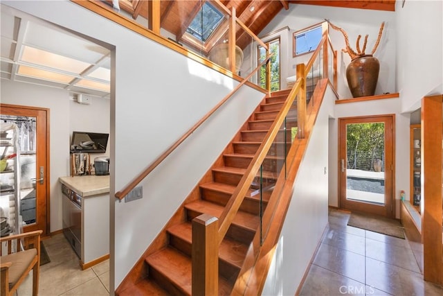 stairs with a skylight, a high ceiling, and tile patterned floors