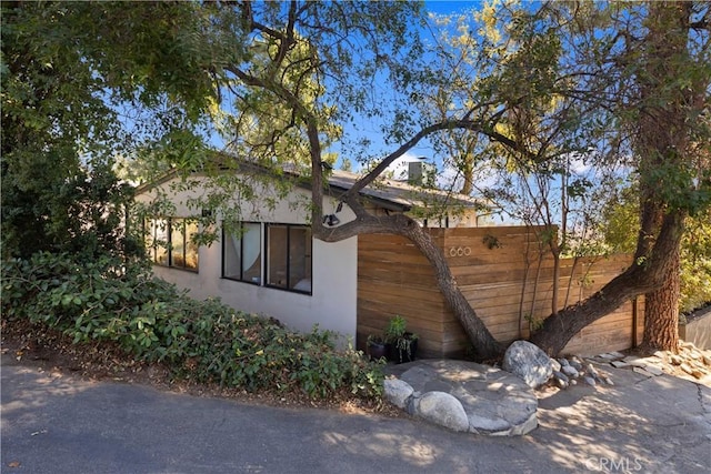 view of side of property featuring fence and stucco siding