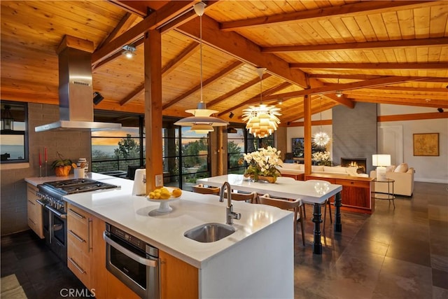 kitchen featuring island range hood, lofted ceiling with beams, open floor plan, stainless steel appliances, and a sink