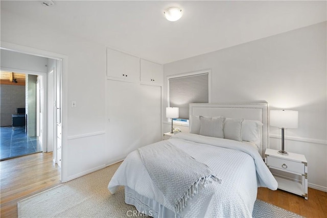 bedroom featuring light wood-type flooring, baseboards, and a closet