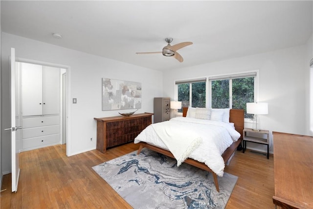 bedroom with ceiling fan, wood finished floors, and baseboards