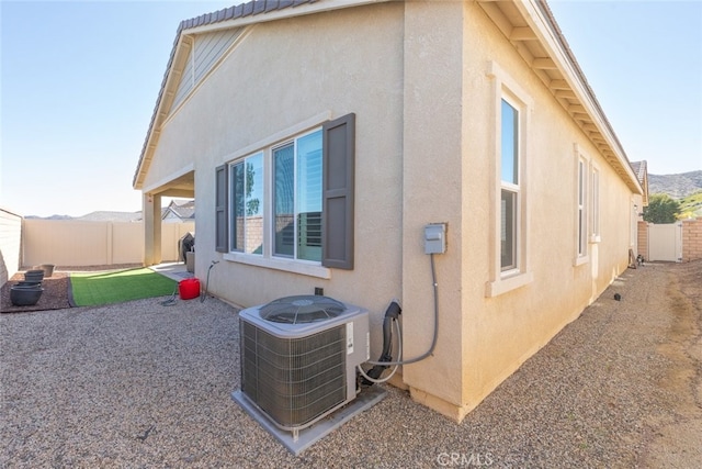 back of property with stucco siding, fence, and central AC unit