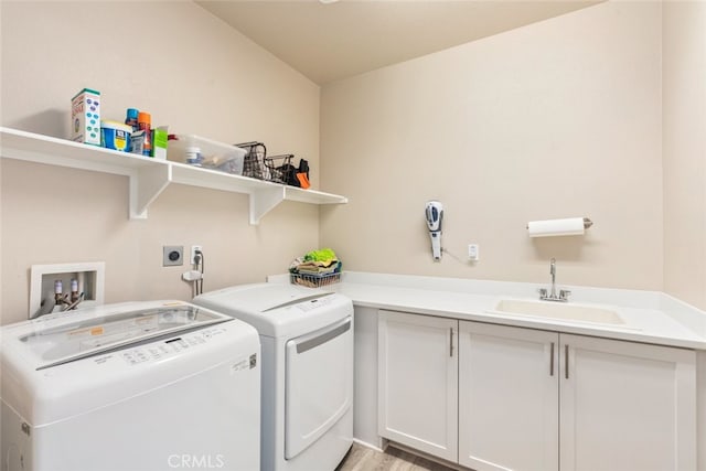 laundry room with cabinet space, washer and clothes dryer, and a sink